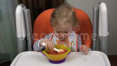一个穿背心和围兜的孩子在一碗汤里拿着勺子